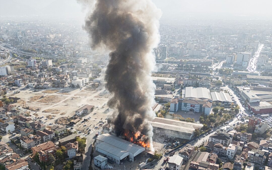 Vista aérea de un incendio en una nave con llamas y una columna de humo
